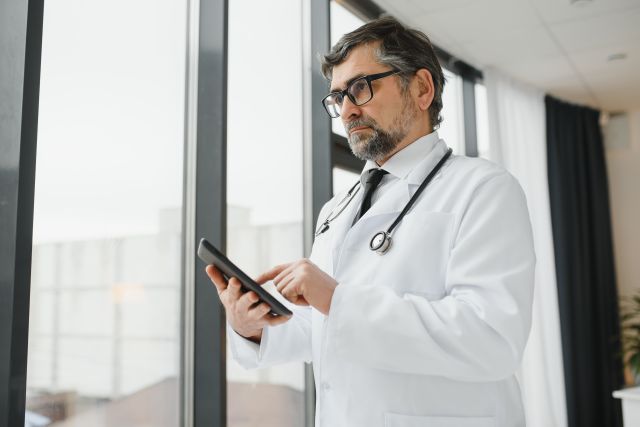 Arzt nutzt telemedizinische Dienste mit Tablet Computer.